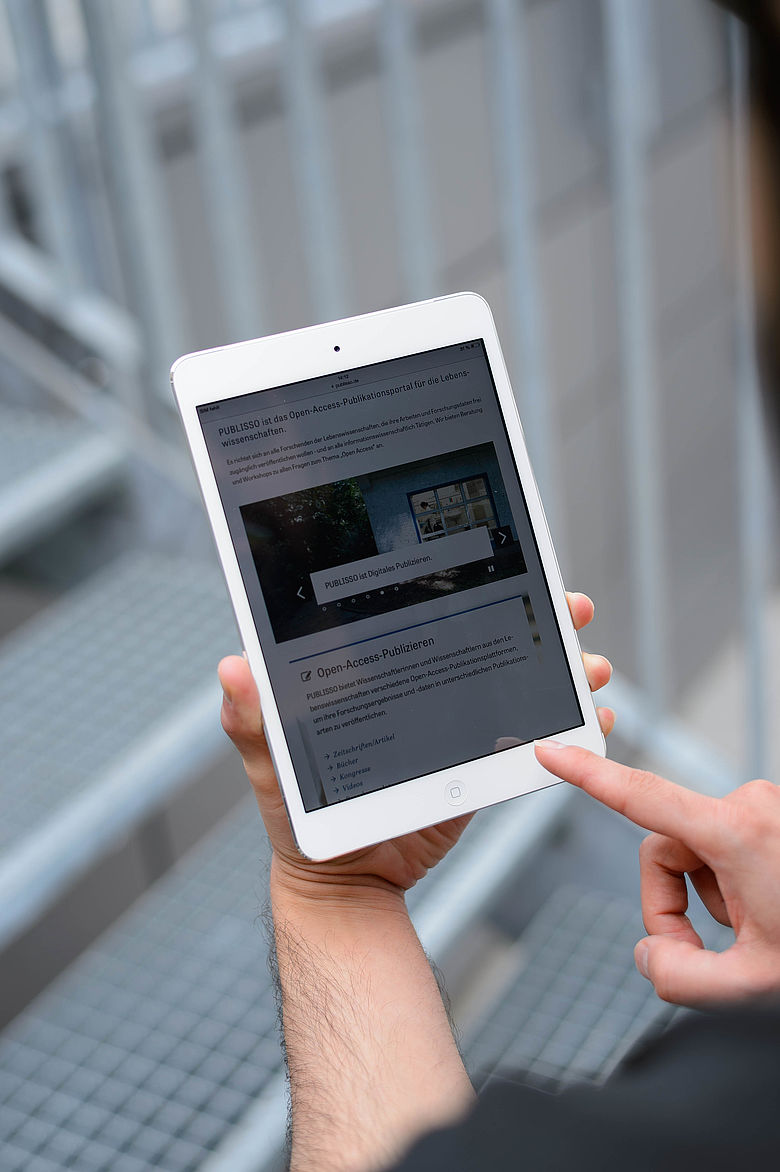 Zwei H&auml;nde an einem Tablet, auf dem Bildschirm PUBLISSO, das Publikationsportal von ZB&nbsp;MED