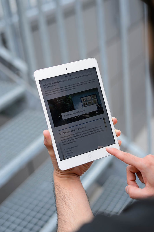 Zwei H&auml;nde an einem Tablet, auf dem Bildschirm PUBLISSO, das Publikationsportal von ZB&nbsp;MED