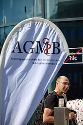 Beachflag mit AGMB-Logo. Männliche Person im Hintergrund.