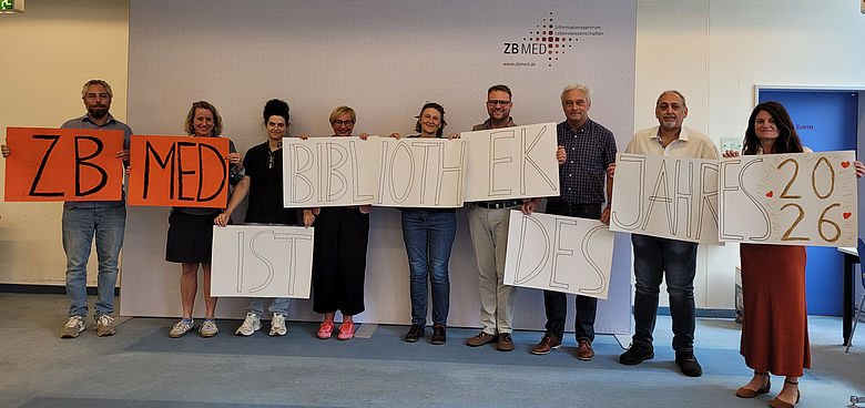 Nine ZB&nbsp;MED staff members are holding up several posters bearing the words &lsquo;ZB&nbsp;MED is Library of the Year 2026&rsquo;